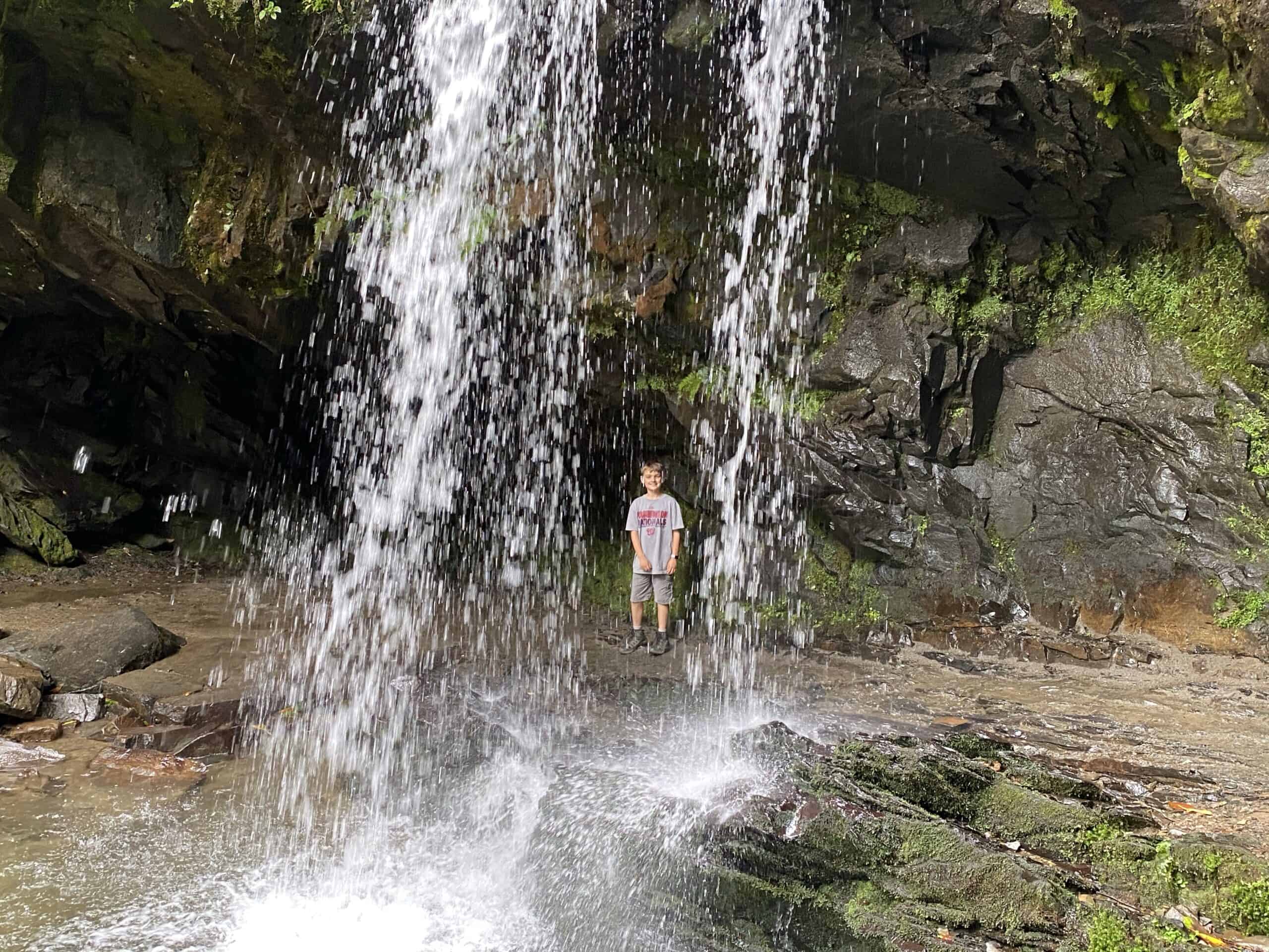 Walking a behind a waterfall at Grotto Falls at Rocky Mountain National Park in spring