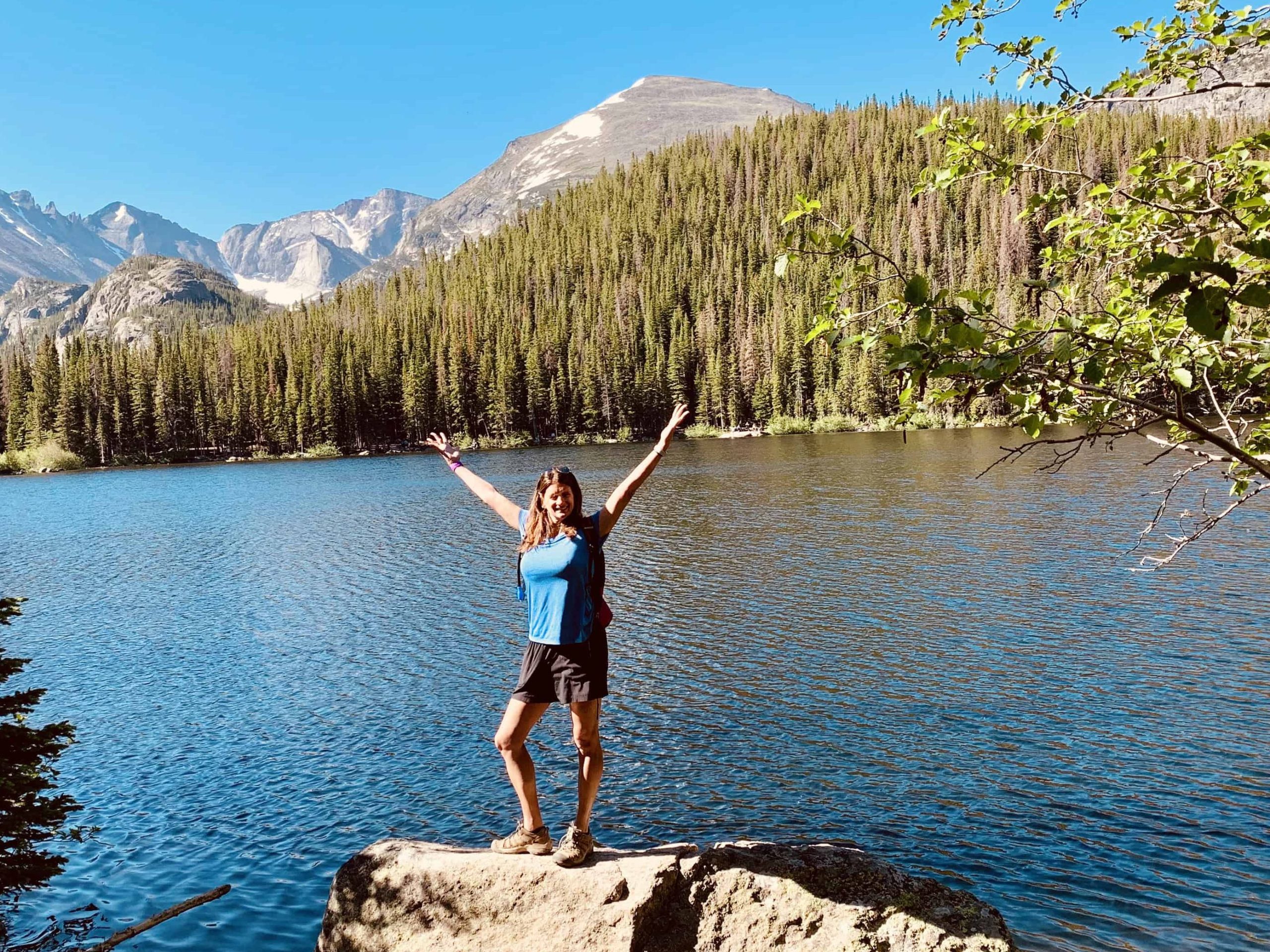 Hiker celebrating the view at the Emerald Lake on the Five Lakes Trail of Rocky Mountain National Park in Estes Park