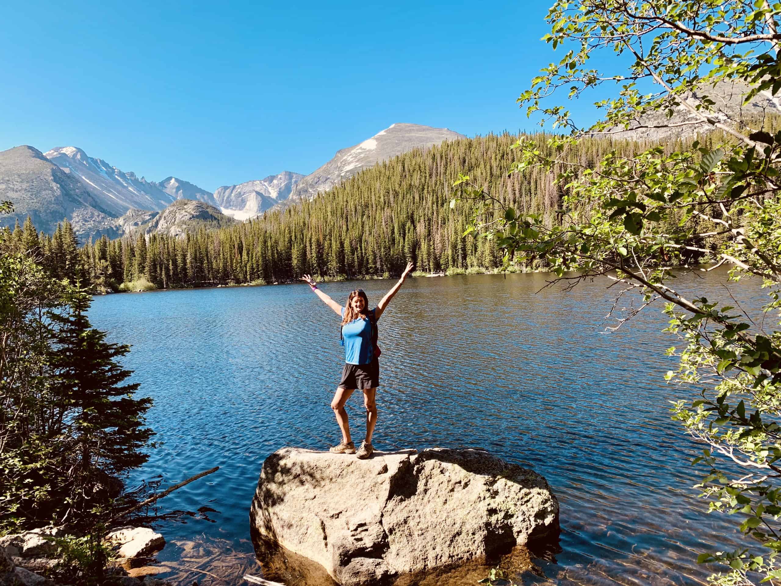 Hiker celebrating the view at the Emerald Lake on the Five Lakes Trail of Rocky Mountain National Park in Estes Park