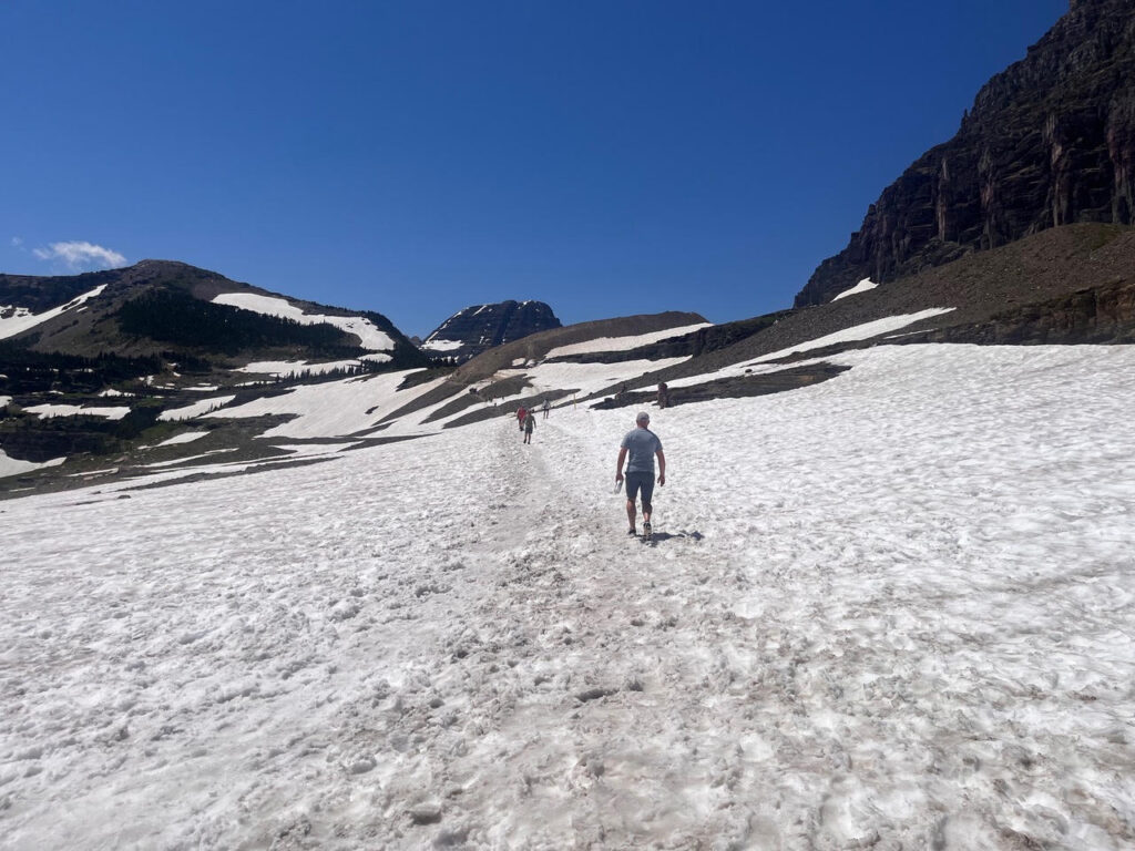 Hiking the Hidden Lake Overlook Trail at Logan Pass on snow in Glacier National Park