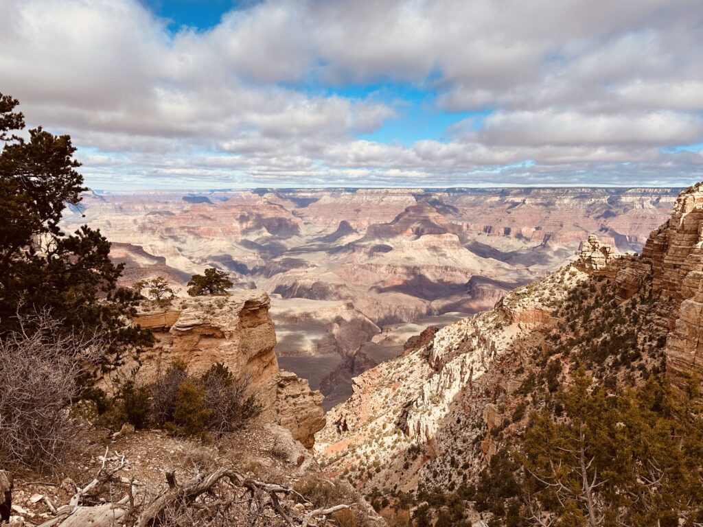 Panoramic view of the Grand Canyon South Rim at sunset, featuring deep red rock layers and golden light hitting the peaks.