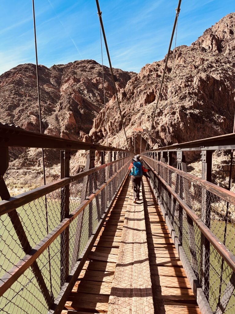 "A steep, winding hiking trail descending into the Grand Canyon, with hikers visible in the distance.