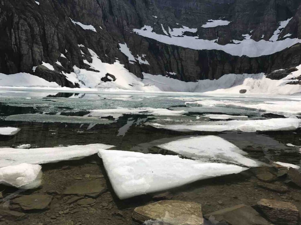 Crystal clear blue water reflecting the mountain peaks at Lake McDonald in Glacier National Park.