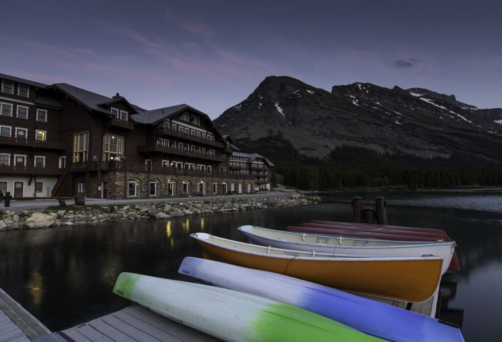 View of Many Glacier hotel and canoes on Swiftcurrent lake with mountains of Glacier National Park in the background