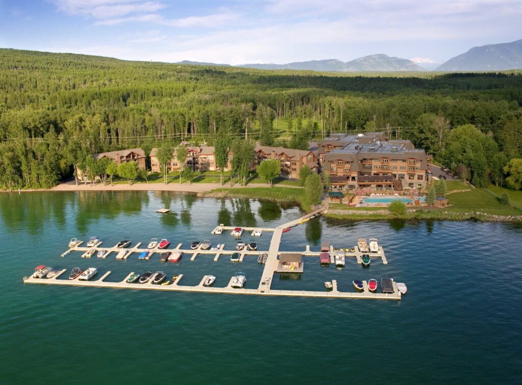 Aerial view of The Lodge at Whitefish Lake and boat docks with Glacier National Park in the background.