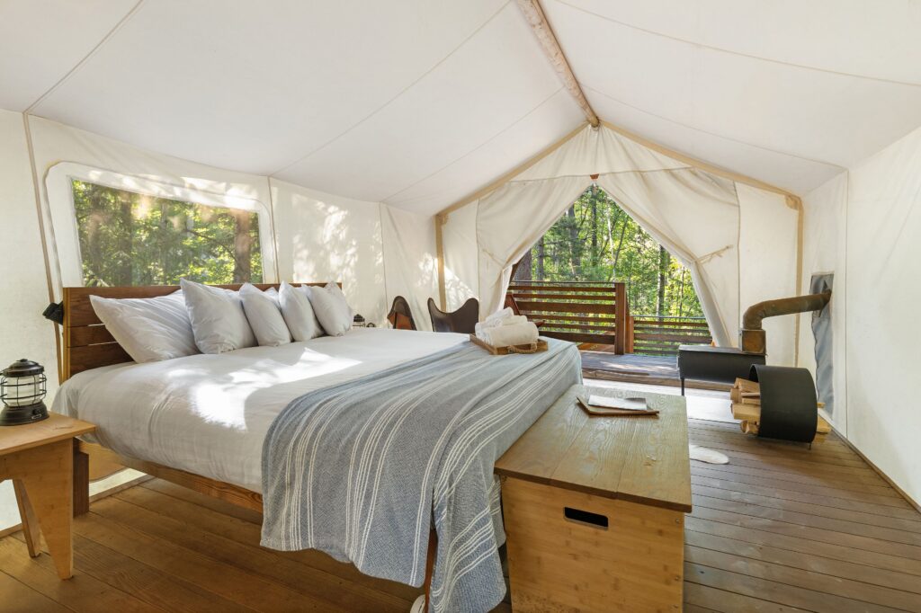 A glamping tent at Under Canvas with a bed and fireplace and beautiful view of Glacier National Park