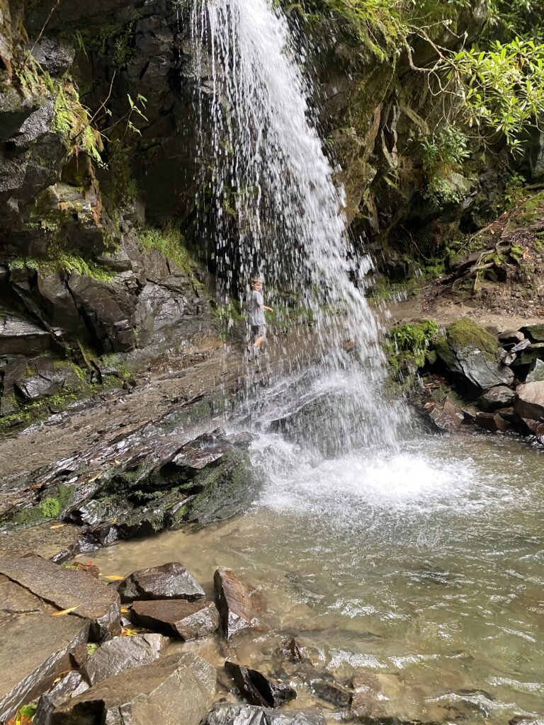 Child walking behind a waterfall in Great Smoky National Park