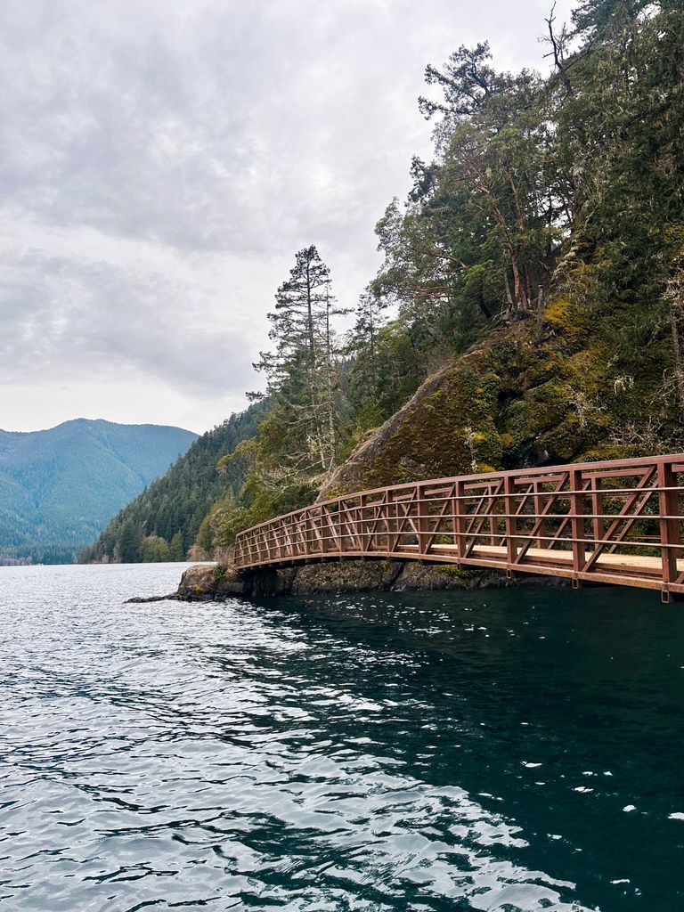 A serene landscape of Lake Crescent with a wooden bridge and lush forest in Port Angeles, WA.