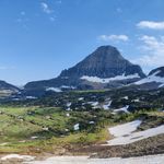 Expansive view of mountains and valleys in Glacier National Park with clear blue skies.